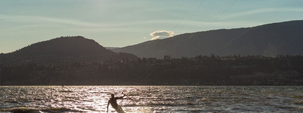 kelowna sunset shot of the okanagan lake in which a man is kiteboarding